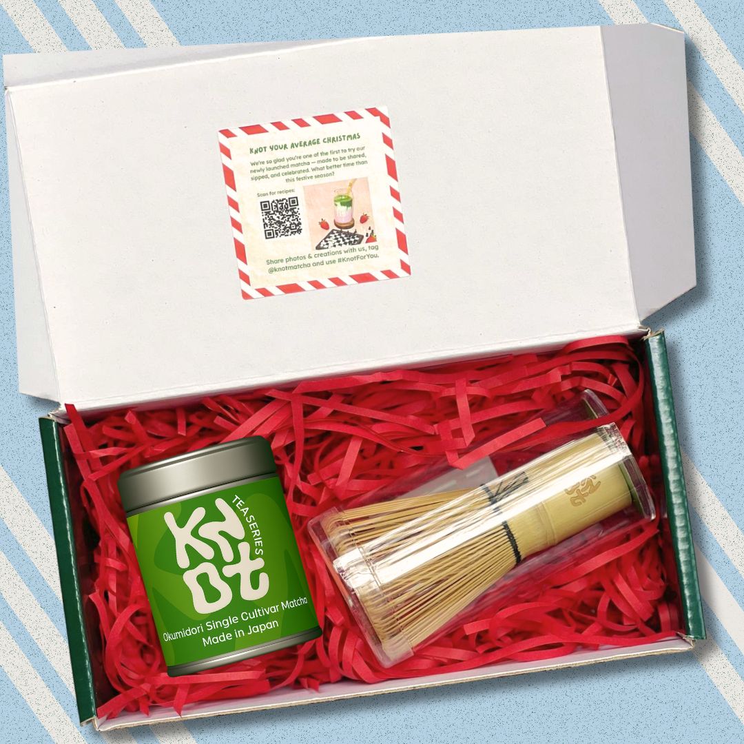 Tea set with a green tea canister and wooden whisk in a box on a striped background