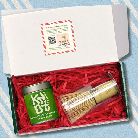 Tea set with a green tea canister and wooden whisk in a box on a striped background