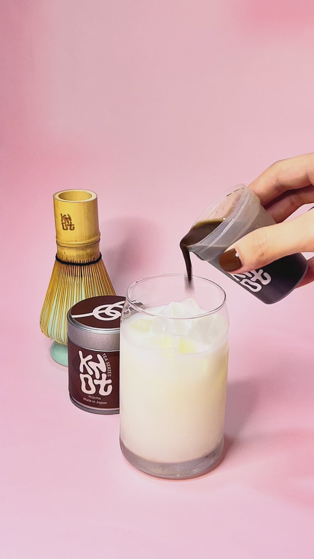 Hojicha latte pour with pink background